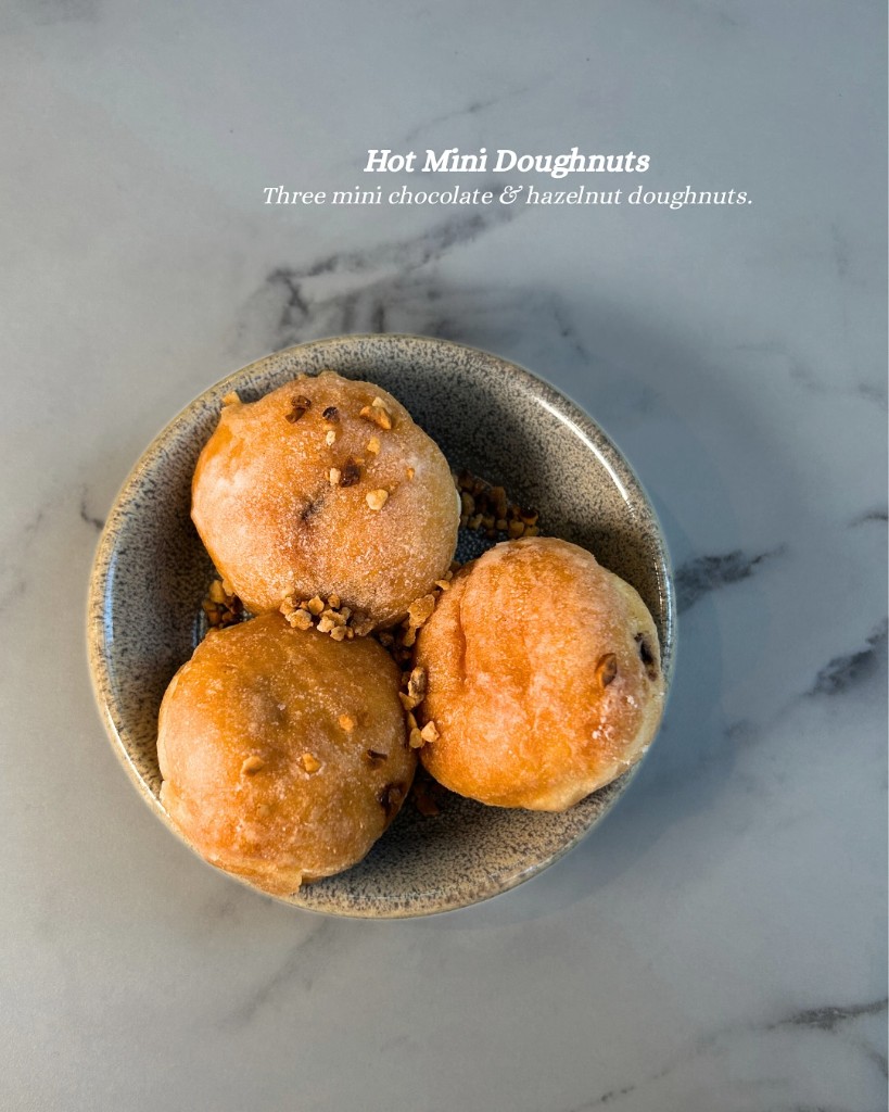 Hot mini doughnuts in a speckled bowl on marble