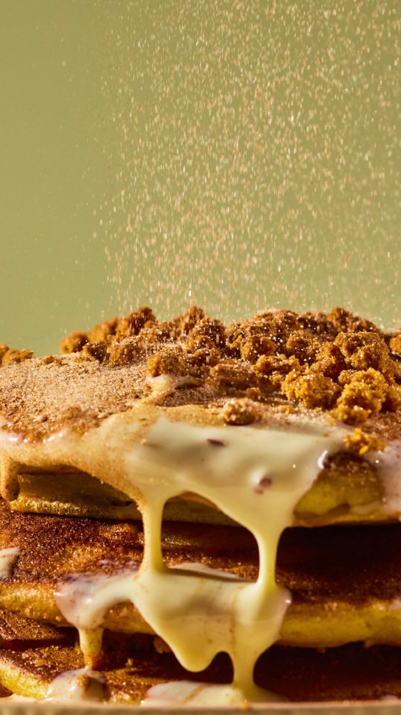 Stacked pancakes with glaze and falling cinnamon dust