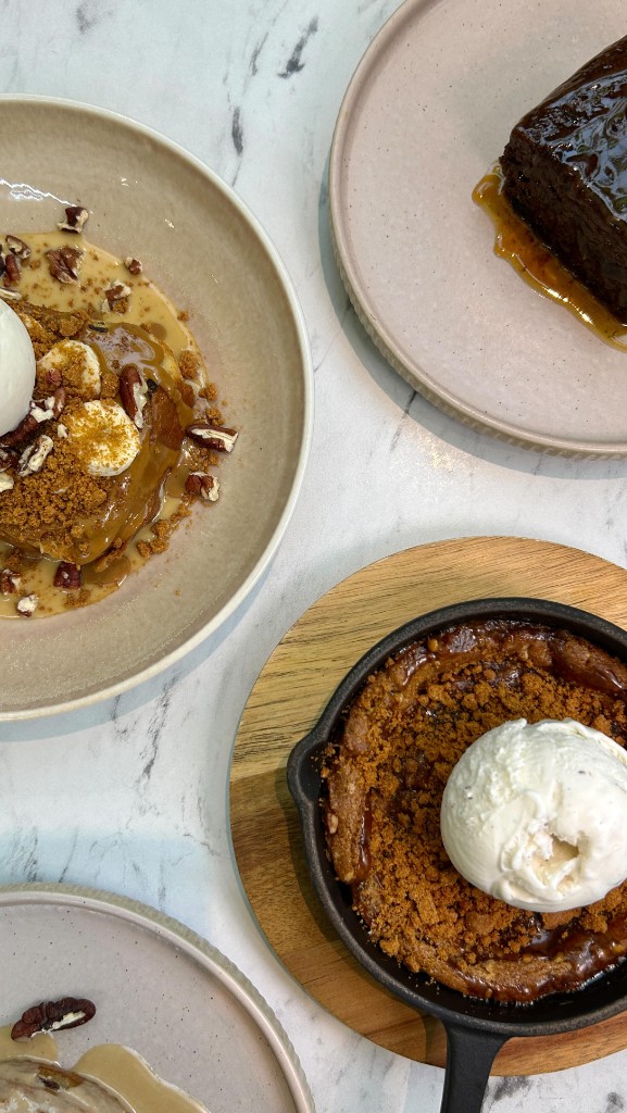 Overhead view of four plated warm desserts on white marble
